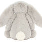 The Jellycat Bashful Silver Bunny plush, in light gray with long floppy ears and a round white tail, sits with its back to the camera—perfect as a bedtime story companion.