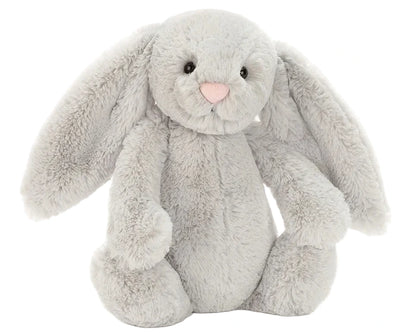 The Jellycat Bashful Silver Bunny is a soft plush with floppy ears, black button eyes, and a pink nose, shown sitting upright against a plain white background—ideal for bedtime cuddles.