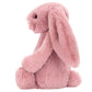 Side profile of a dusty pink Bashful Tulip Pink Bunny plush sitting down.