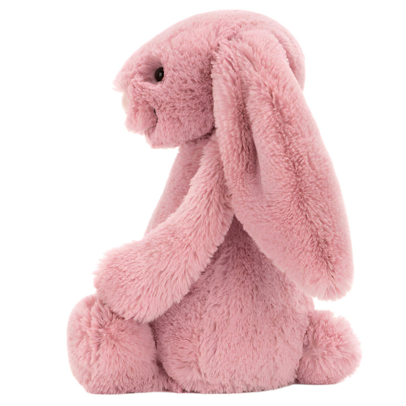 Side profile of a dusty pink Bashful Tulip Pink Bunny plush sitting down.