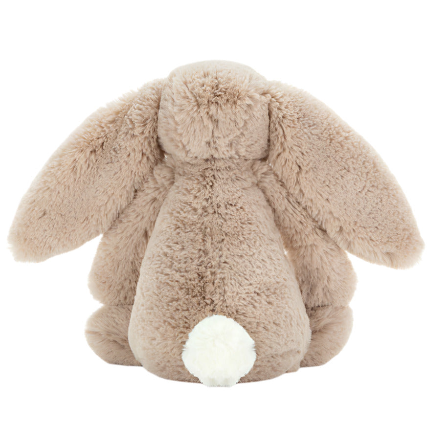The Jellycat Bashful Bunny Beige Medium is a soft plush toy with floppy ears and a white tail, sitting sweetly with its back to the camera.