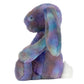 The Jellycat Zodihop Luxe Bunny plush features multicolored pastel fur with a cosmic pattern and a white tail, shown in profile view against a white background.
