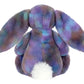 The Jellycat Zodihop Luxe Bunny features long floppy ears, a cosmic multicolored purple and blue fur pattern, and a fluffy white tail, shown from the back.