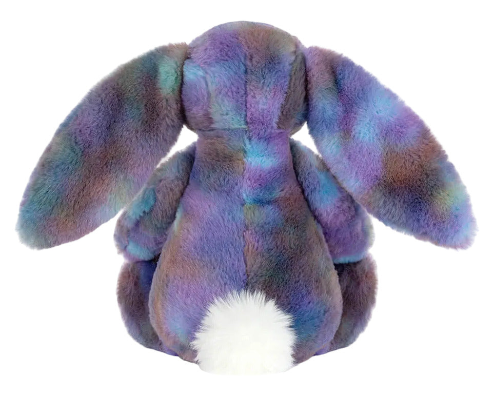 The Jellycat Zodihop Luxe Bunny features long floppy ears, a cosmic multicolored purple and blue fur pattern, and a fluffy white tail, shown from the back.