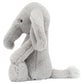 Bashful Luxe Elephant Thuddeus by Jellycat is a plush gray elephant with a large trunk, floppy ears, and a fluffy tail sitting upright against a white background.