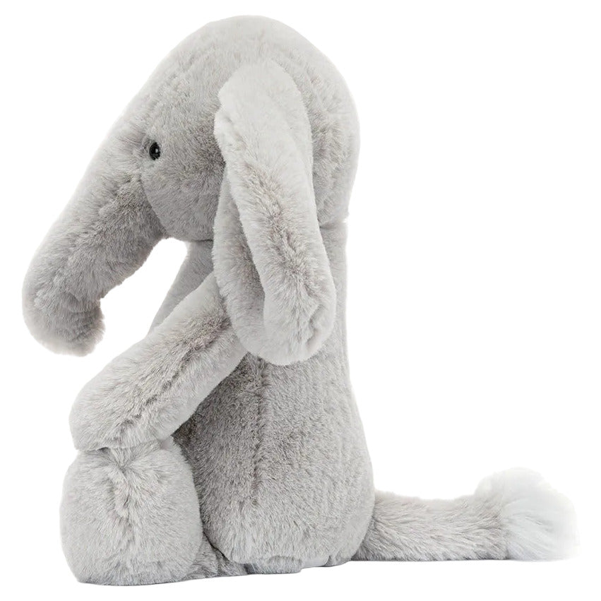 Bashful Luxe Elephant Thuddeus by Jellycat is a plush gray elephant with a large trunk, floppy ears, and a fluffy tail sitting upright against a white background.