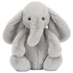A gray Bashful Luxe Elephant Thuddeus plush by Jellycat with big ears and a long trunk, sitting upright and facing forward.