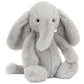 A soft, gray Bashful Luxe Elephant Thuddeus by Jellycat with floppy ears, a long trunk, black button eyes, and a small tail sits upright against a white background.
