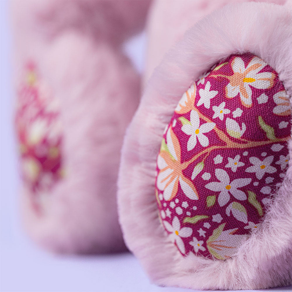 Close-up of a soft, pink Thistlepop Blossom Luxe Bunny Original paw by Jellycat, featuring a floral-patterned pad with white and yellow flowers on a pink background.