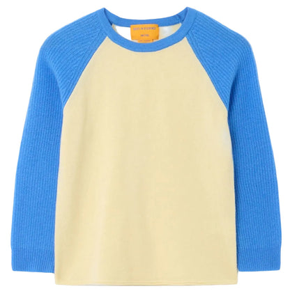 The Baseball Tee by Guest in Residence is a lightweight cashmere long-sleeve shirt with a cream body, colorblock bright blue raglan sleeves, a round neckline, and an orange tag inside the collar.