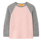 The Guest in Residence Baseball Tee is a lightweight cashmere top with a light pink body and gray colorblock raglan sleeves, shown against a white background.
