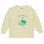 Beige Bonton Boys' Paradise Sweatshirt with ribbed cuffs and green surfing graphic. Features "WELCOME TO PARADISE" and "BONMOM" text. Soft cotton for comfort—meet the Sweatshirt Vanilla Paradise.