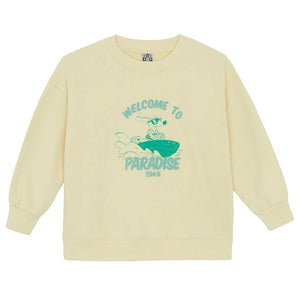 Beige Bonton Boys' Paradise Sweatshirt with ribbed cuffs and green surfing graphic. Features "WELCOME TO PARADISE" and "BONMOM" text. Soft cotton for comfort—meet the Sweatshirt Vanilla Paradise.