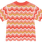 The Girls' Ninon Knit Top by Bonton is a 100% cotton short-sleeve crochet knit with coral, pink, mustard, and white zigzag stripes plus scalloped hems and handmade finishes.