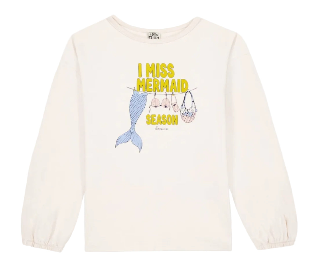 The Bonton Girls’ Mermaid Patch T-Shirt is a white long-sleeve top adorned with “I MISS MERMAID SEASON” text above charming patches of a mermaid tail, shells, and a net bag hanging on a clothesline.