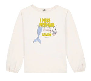The Bonton Girls’ Mermaid Patch T-Shirt is a white long-sleeve top adorned with “I MISS MERMAID SEASON” text above charming patches of a mermaid tail, shells, and a net bag hanging on a clothesline.