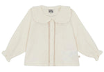 The Baby Girls’ and Toddler Fig Shirt by Bonton is a cream-colored long-sleeve shirt featuring a ruffled Peter Pan collar, front buttons, lace trim, and elastic cuffs, displayed on a white background.