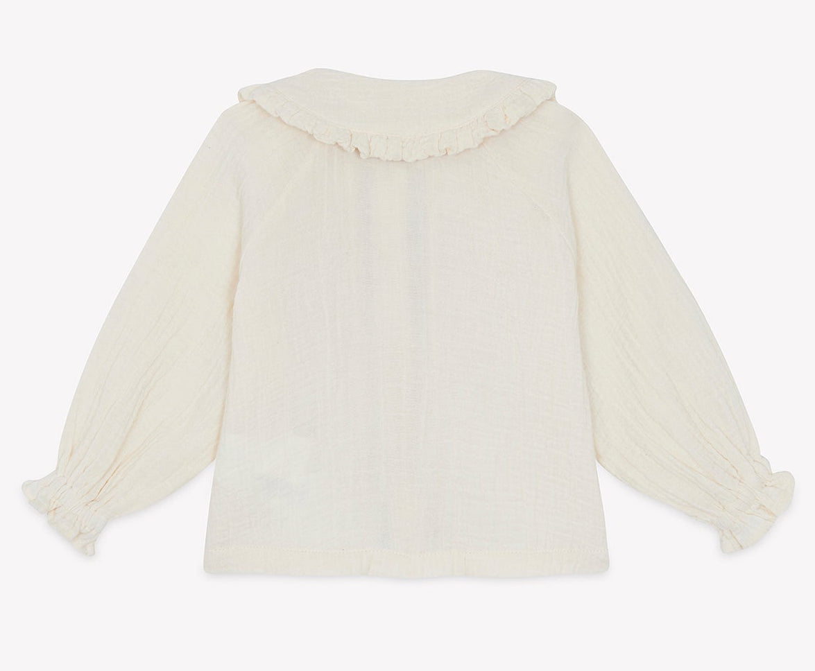 Back view of the Bonton Baby Girls’ and Toddler Fig Shirt, a long-sleeved, off-white top featuring a Peter Pan collar with delicate ruffles and gathered cuffs, displayed on a plain background.