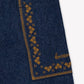 Close-up of the Bonton Girls’ Lauren Pant, highlighting a chambray cotton pocket detailed with mustard yellow embroidery and the word “bonjour” stitched in cursive.