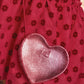 Close-up of a person wearing a red skirt with floral patterns, carrying the Bonton Girls’ Leather Heart Bag in shiny pink leather with a small embossed logo.
