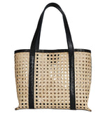 The Bembien Margot Bag, Mini by Bembien is a beige rattan cane tote handwoven in Bali, featuring black leather straps and trim with a perforated design.