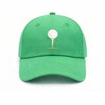 The Bits & Bows Tee Time Hat is a vibrant green baseball cap featuring an embroidered white golf ball resting on a tan tee over a patch of grass, shown against a white background.
