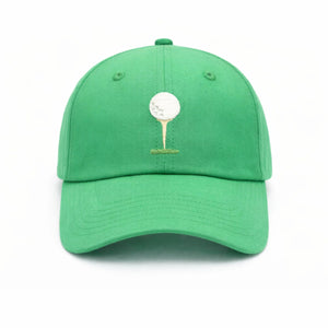 The Bits & Bows Tee Time Hat is a vibrant green baseball cap featuring an embroidered white golf ball resting on a tan tee over a patch of grass, shown against a white background.