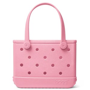 The Bitty Bogg Bag - Shimmer by Bogg Bags is perfect for Mommy and Me outings. Its pink color, two handles, rectangular shape, textured surface, and circular hole pattern make it a must-have for any Bogg lover.