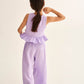 A girl with long brown hair in a ponytail wears Cozmo's Girls' Violet Wide Pants, featuring an elastic waistband, as she stands with her back to the camera against a plain background.