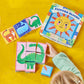 A child arranges Eeboo’s Simple Things Picture Blocks—a 9-block wooden set forming a dinosaur—while the box and easy tiger and whale puzzles sit on a yellow surface.