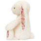 Blossom Cream Bunny ‘Berry’ by Jellycat sits upright on a plain background, featuring charming floral fabric on the inside of its ears and feet—a delightful plush bunny stuffed animal perfect for cuddling or display.