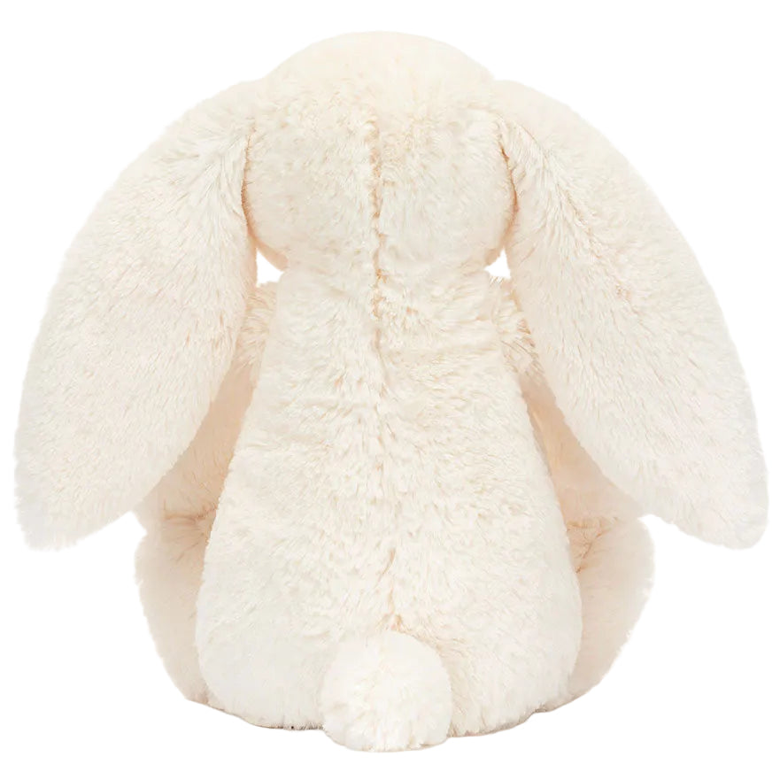 A plush Jellycat Blossom Cream Bunny ‘Berry’ is shown from the back, featuring long floppy ears and a small round tail, reminiscent of the brand’s classic bunny stuffed animals.