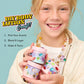 A smiling child holds colorful Create Your Own Body Lotion containers by Super Smalls; image text highlights the steps: pick your scents, blend & layer, and make it yours—perfect for a fun and creative kids body lotion kit activity.