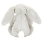 The Jellycat Blossom Silver Bunny 'Bloom' Small boasts bashful fur, long ears, and a charming white tail, sitting cozily while facing away.