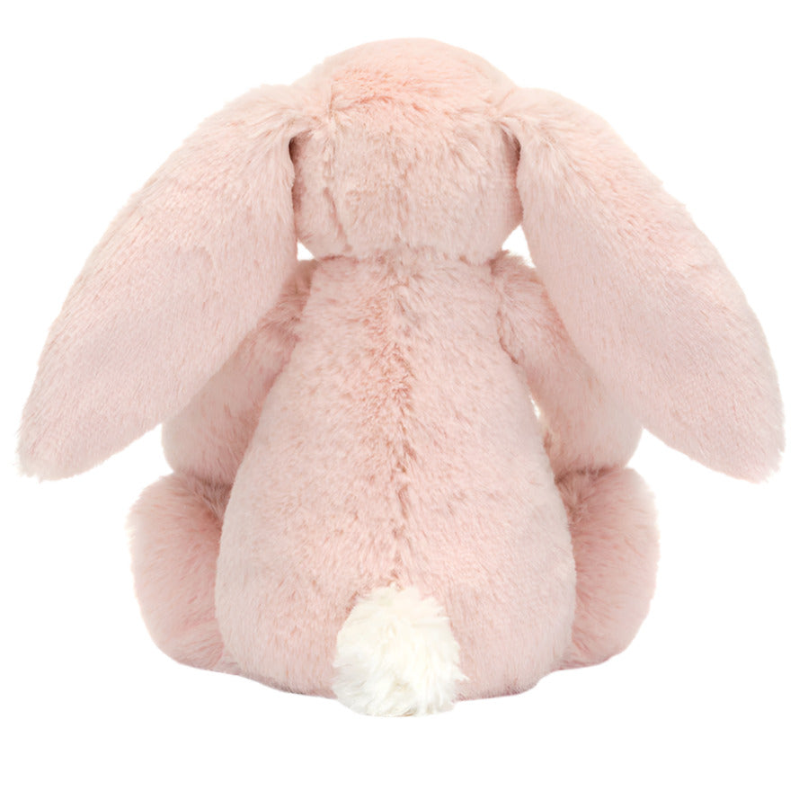 A Jellycat Blossom Blush Bunny ‘Cherry’ plush sits facing away, showing its long floppy ears and white tail.