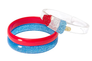 The Lillies & Roses Popsicle Rocket Glitter Red Blue Bangles set features three playful bracelets: one red, one blue with glitter, and one clear with a glittery red, white, and blue popsicle—ideal festive patriotic jewelry.
