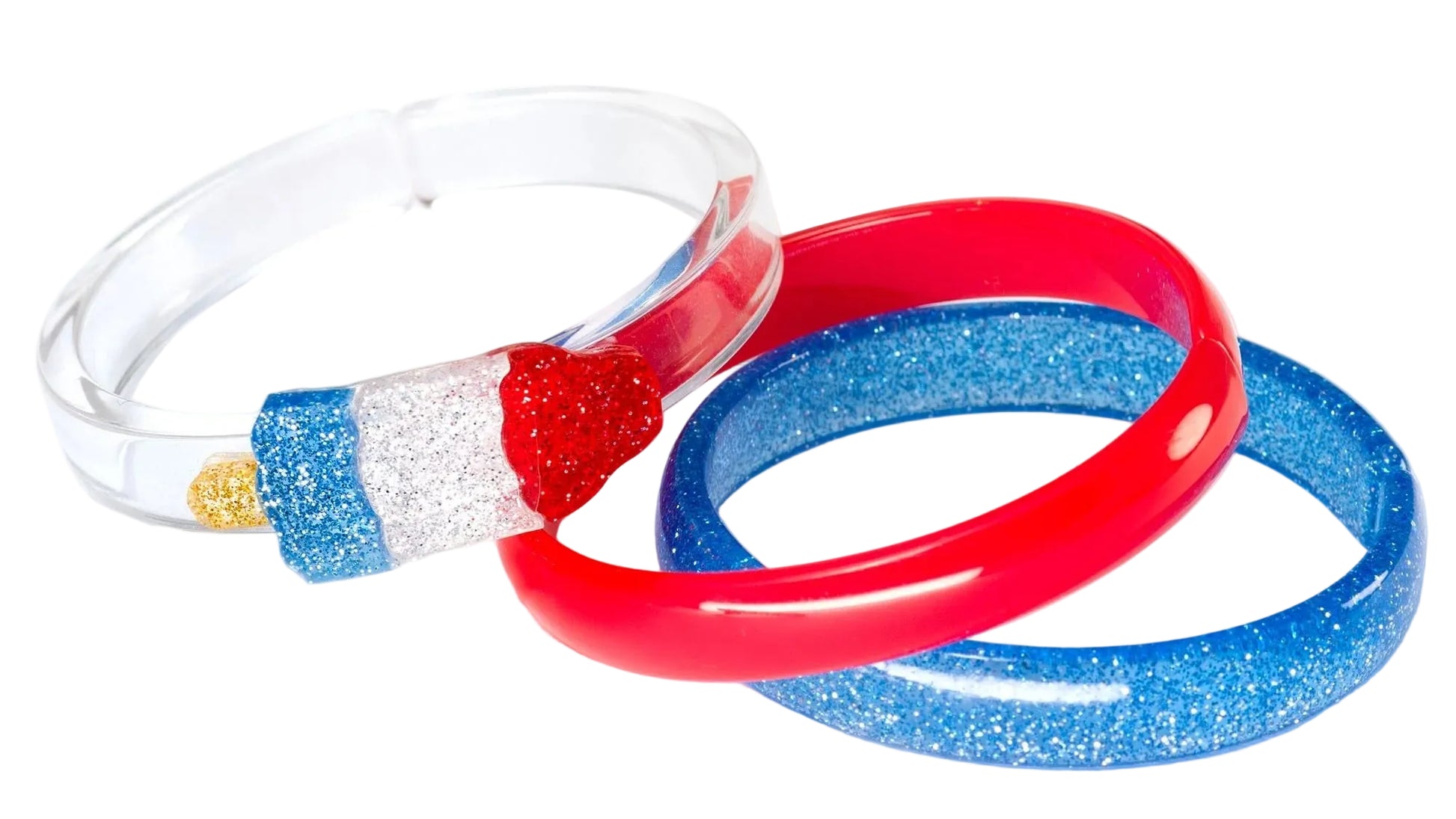 The Lillies & Roses Popsicle Rocket Glitter Red Blue Bangles set includes three plastic bangles—one clear with a popsicle design, one red, and one blue with glitter—for a playful patriotic accessory.
