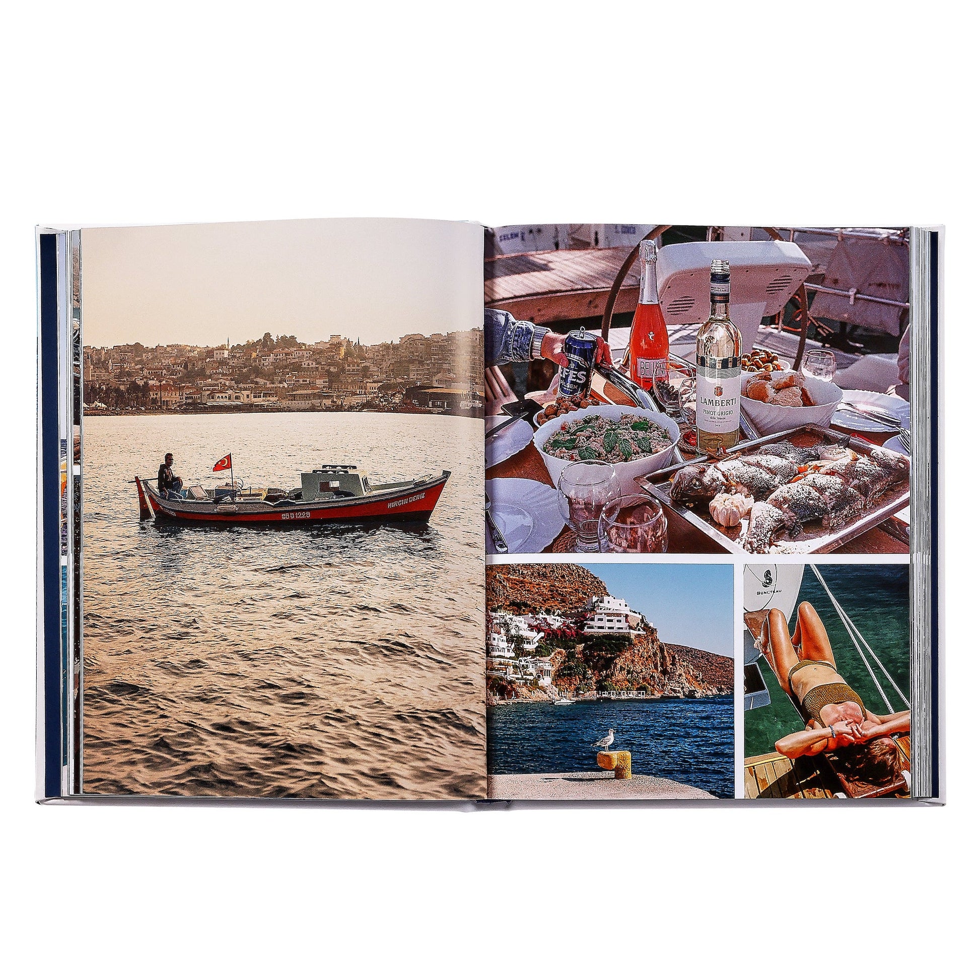 The open book "Boatlife: Exploring the Freedom of Maritime Living" by Graphic Image reveals images of boat life—fishing boats on water, seafood feasts, coastal scenery, and sunbathers by the sea.