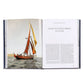Open to a photo of a red-sailed cutter on the ocean beside "Sailing the Scottish Hebrides in a Cutter," Boatlife: Exploring the Freedom of Maritime Living by Graphic Image inspires dreams of maritime adventure and nomadic living.
