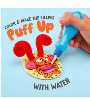 A hand uses a blue water dropper to apply water to a colorful crab craft, making red pipe cleaner shapes puff up. Text reads: "Color & make the shapes puff up with water using Puffy Pages by Bright Stripes." Dive into creative on-the-go fun as you bring sea animals to life in vibrant 3D scenes!.