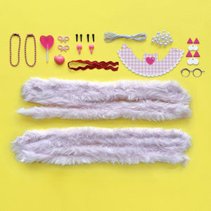 A colorful assortment of DIY Chenille Cuties - Cats by Bright Stripes, including faux fur strips, headbands, jewelry, glasses, pipe cleaner kitties, and decorative pieces in pink, white, and red are neatly arranged on a yellow background.