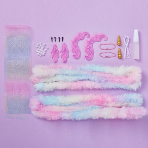 DIY Chenille Cuties - Unicorns by Bright Stripes: Components of this magical unicorn craft kit are displayed on a purple background—featuring pastel faux fur strips, glitter fabric, pink felt pieces, beads, gold horns, glue, and cord. Perfect for making your own unicorn bag danglers or keychains! Ideal for pipe cleaner (chenille) craft fans seeking to add an enchanting touch to their accessories.