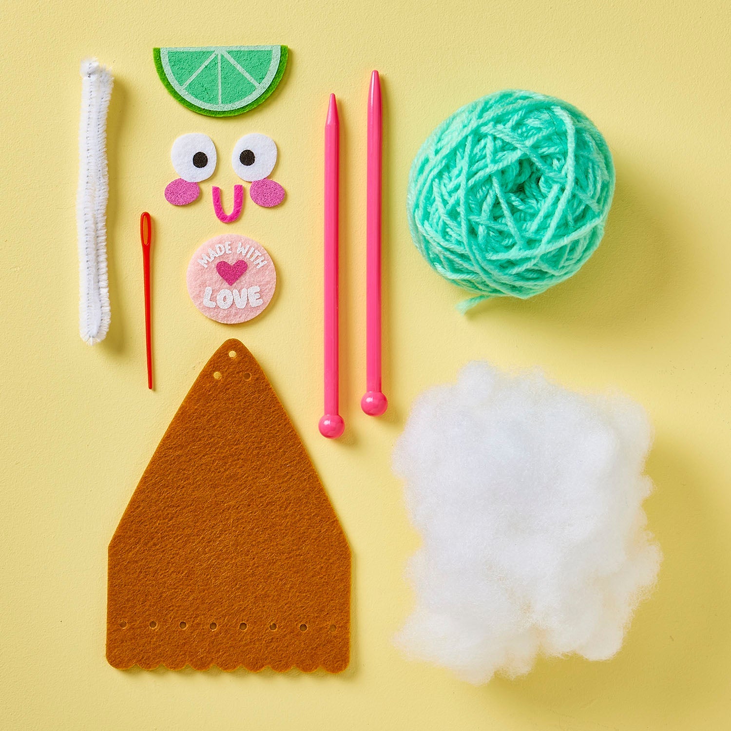Introducing the Snack Knit Kit - Key Lime Pie by Bright Stripes: a beginner-friendly knitting kit featuring teal yarn, two pink needles, felt pieces, a "Made with Love" button, a pipe cleaner, a plastic needle, and stuffing—all beautifully arranged on a yellow background. Perfect for creative craft projects and fun knitting adventures!.