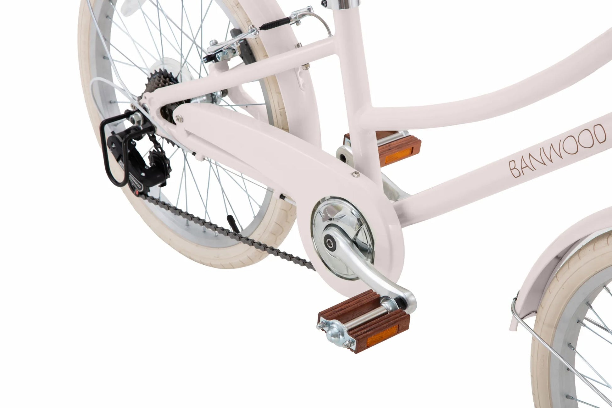 Close-up of the rear section of a light pink Banwood Kids’ Vintage Classic Bike, highlighting its pedal, chain, gear mechanism, rear wheel, and reflectors against a white background. The subtle Scandinavian design details evoke the timeless elegance of vintage bicycles, reimagined for children by Banwood.