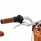 Close-up of the Banwood Kids’ Vintage Classic Bike handlebar featuring a brown grip, brake lever, gear shifter, and a woven basket attached to the front—showcasing Scandinavian design influences. A portion of the matching brown saddle appears on the left, highlighting the timeless elegance inspired by vintage bicycles for children.