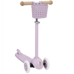 The Banwood Kids’ Eco Scooter with Basket is a lavender three-wheel sustainable scooter for kids, featuring a small front basket, tan handlebar grips, and white wheels, shown on a white background.