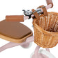 Close-up of the Banwood Kids’ Trike Vintage in pink, featuring a brown seat, leather handle grips, a wicker basket, and a silver bell on the handlebars.