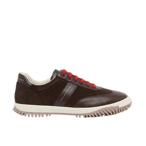 The Stella McCartney Suede Sneaker is a brown low-top inspired by vintage runners, showcasing red laces, a cream sole crafted from compostable rubber, and gold text on the side and heel—expertly displayed on a white background.