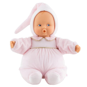 The Corolle Babipouce Sweet Dreams Doll wears a soft light pink outfit with a white and pink hood and single floppy ear, sits upright against a white background, and is machine washable—perfect for cuddles.