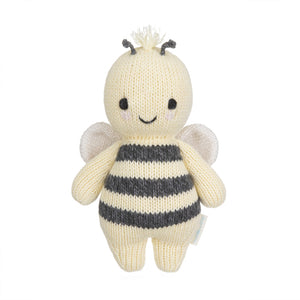 The Cuddle + Kind Bee - Baby 7" is a handcrafted, knitted plush toy featuring black and white stripes, small wings, a smiling face, and short antennae—an heirloom-quality addition to any hand-knit baby animals collection.